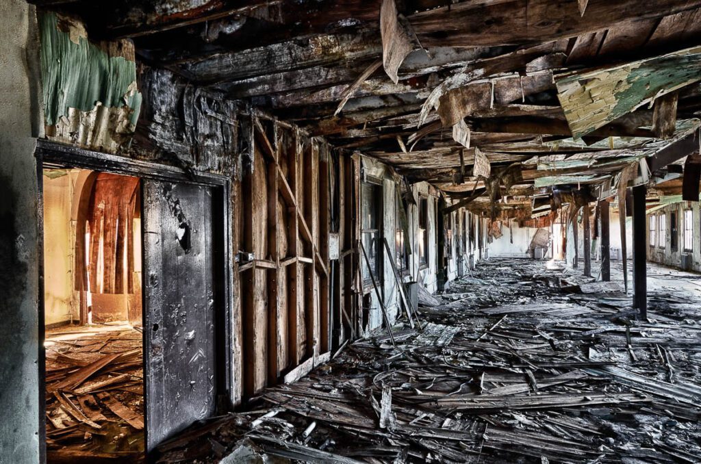 Dilapidated corridor of an abandoned building with debris and fallen ceiling.