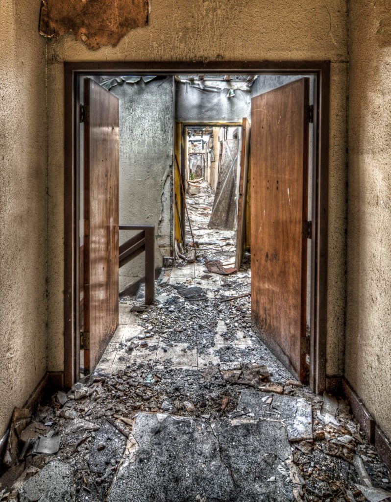 Second floor corridor of an abandoned building with debris and fallen ceiling.