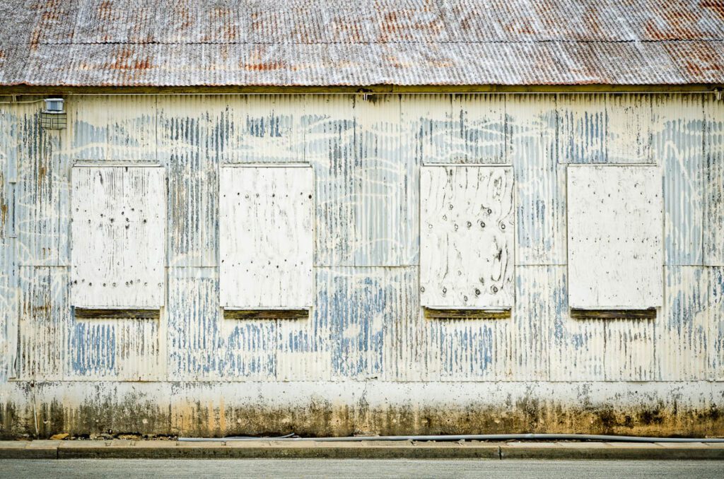 Exterior of a weathered industrial building with boarded windows.