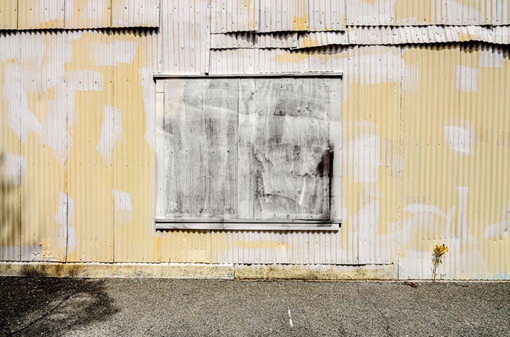Corrugated metal wall with boarded-up window