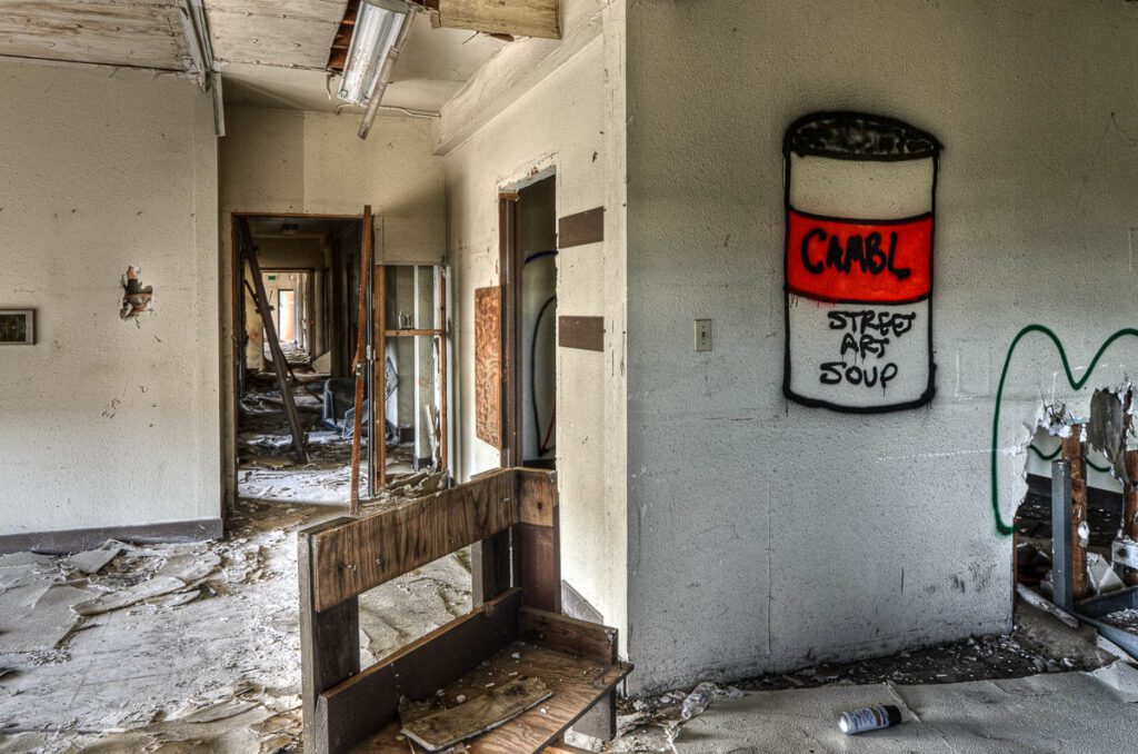 Abandoned interior with graffiti of soup can on wall.