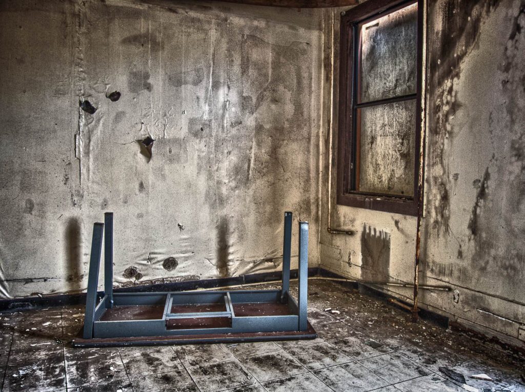 Abandoned room with flipped metal table and weathered walls