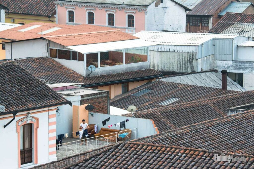 Man hanging laundry to dry on rooftop in Old Town, Quito, Ecuador