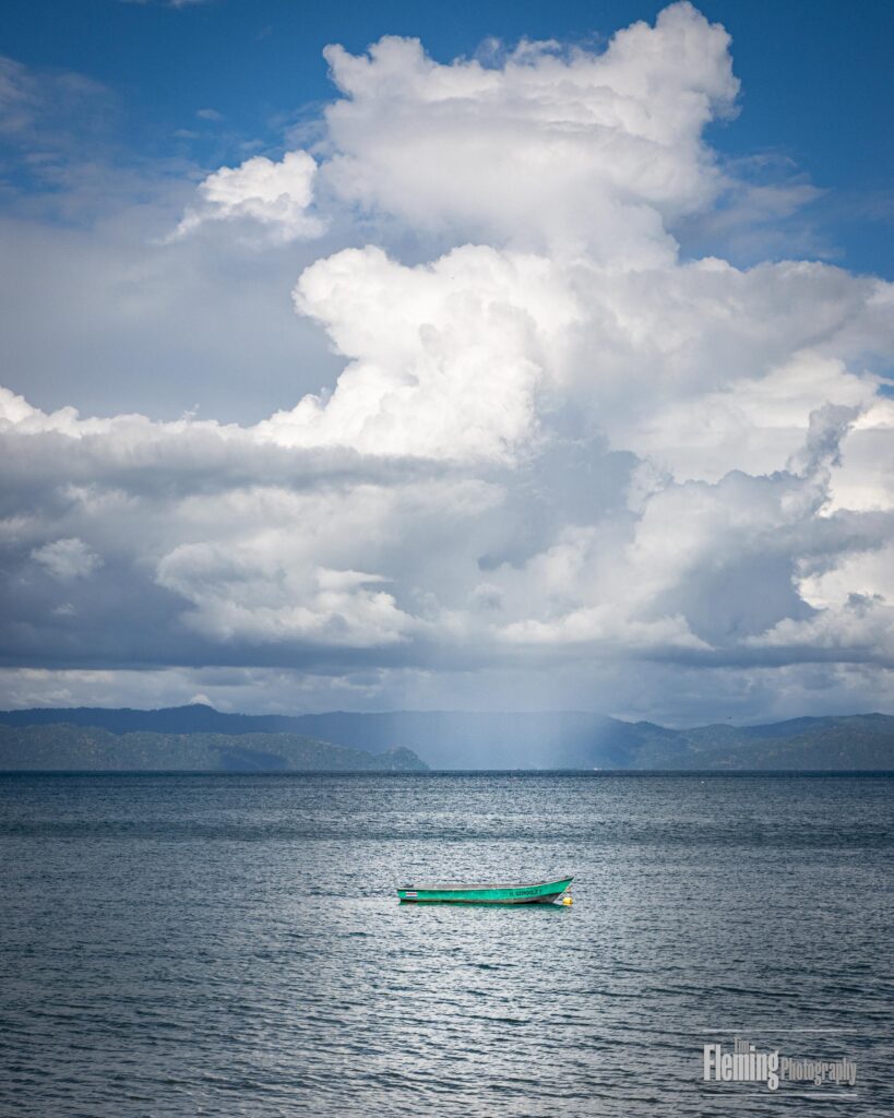 Clouds over a green boat on a beautiful bay, rain in the distance