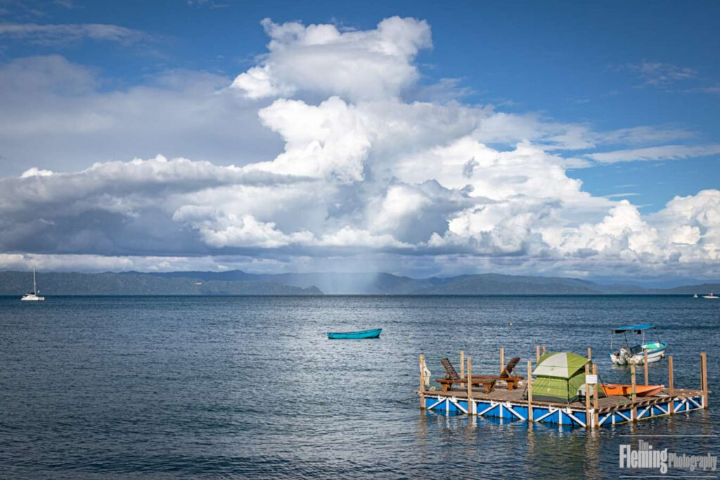 Floating boats, beautiful white clouds and blue sky in scenic Puerto Jiménez