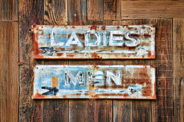 Weathered restroom signs on wood by tim fleming