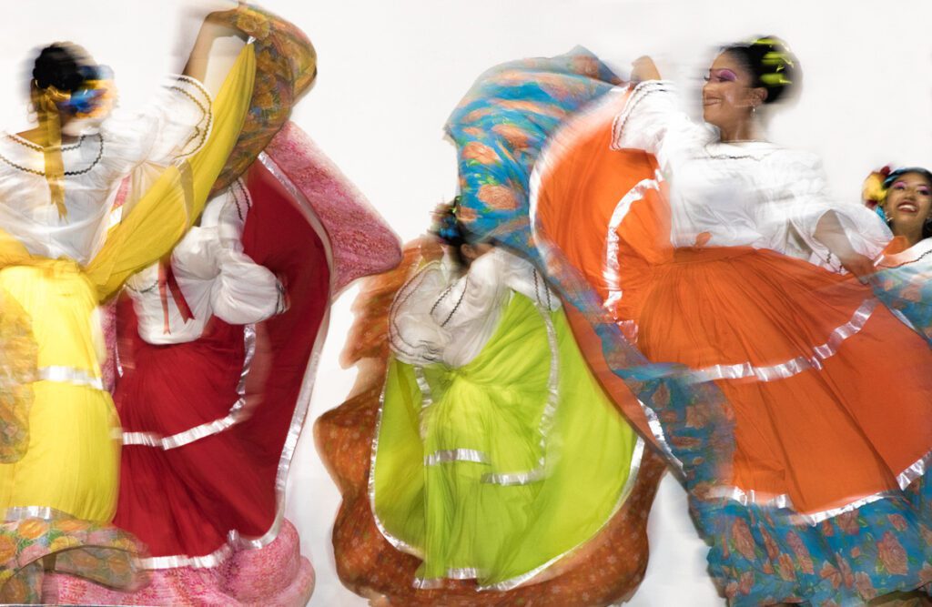 Women in traditional Mexican dresses performing a vibrant dance.