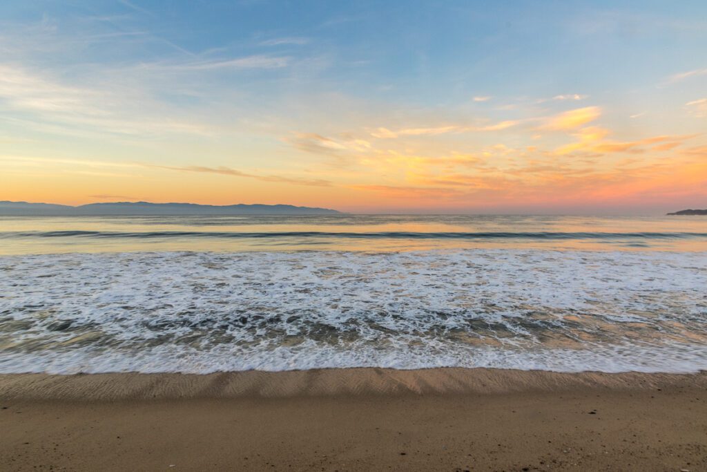 Sunset over a calm ocean with gentle waves