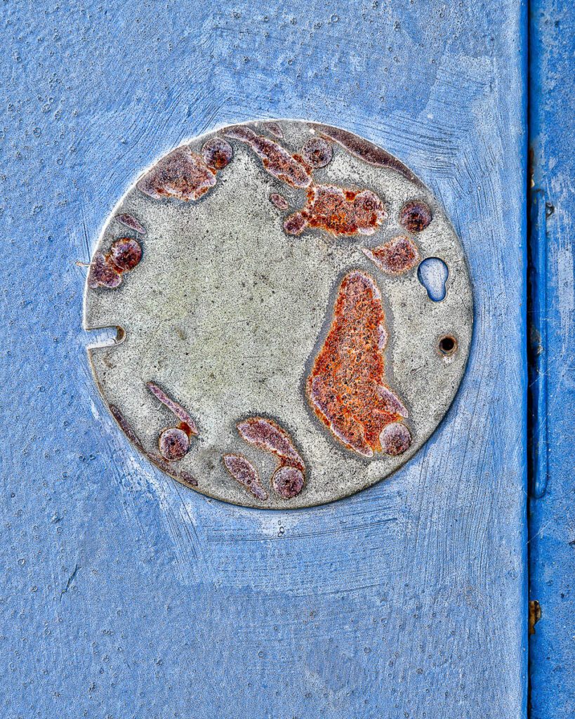 Close-up of a rusted metal circle on a textured blue surface.