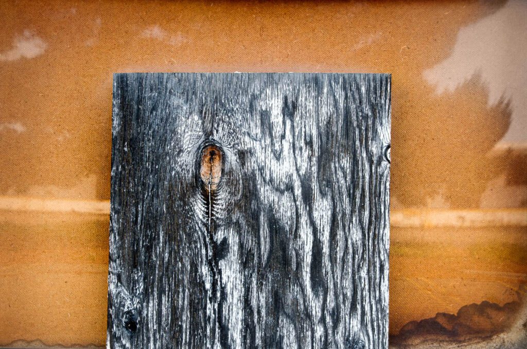 Close-up of weathered wooden board against a rust-colored background.