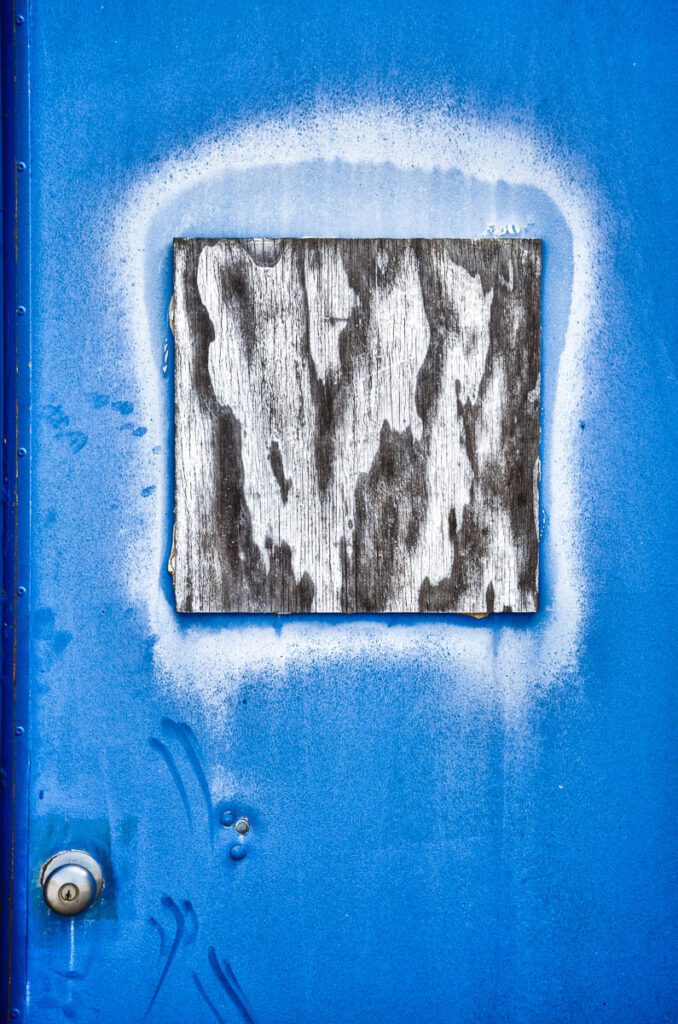 Blue metal door with a weathered wooden panel.