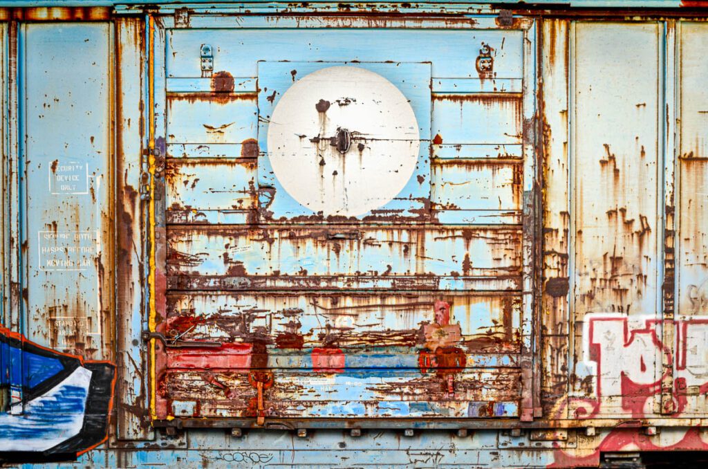Rusty blue cargo door with graffiti and textures.