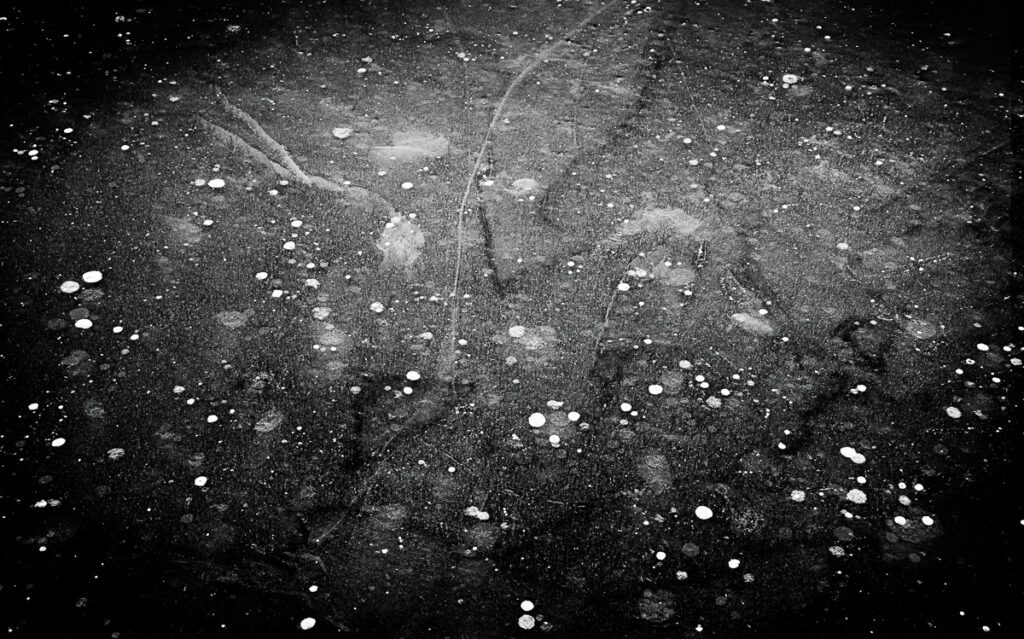 Abstract black and white image with scattered white specks resembling stars or bubbles.