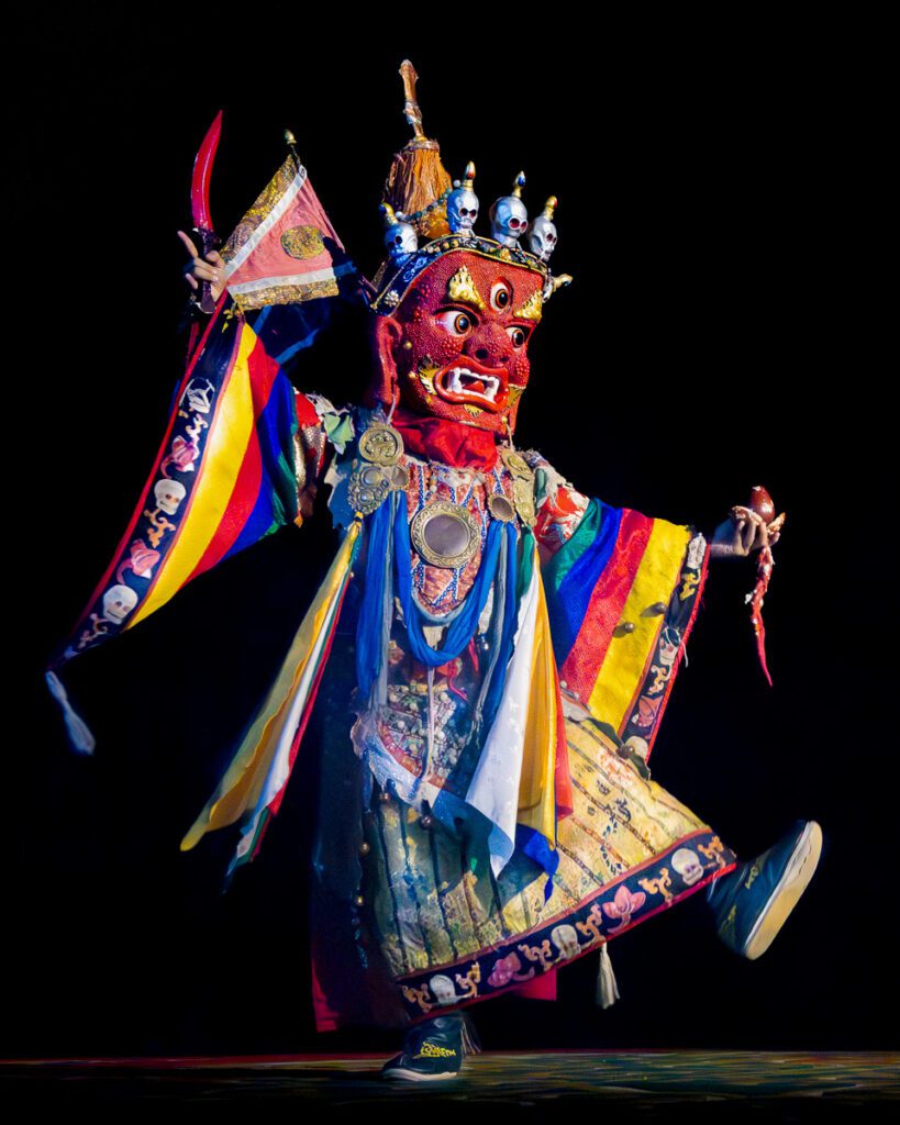 Traditional Mongolian Tsam mask dancer on stage performing a colorful cultural dance.