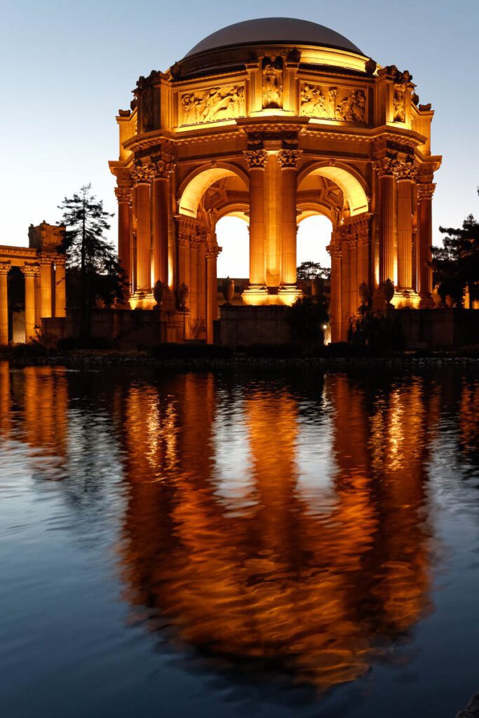 Palace of Fine Arts illuminated at dusk with reflection in water.
