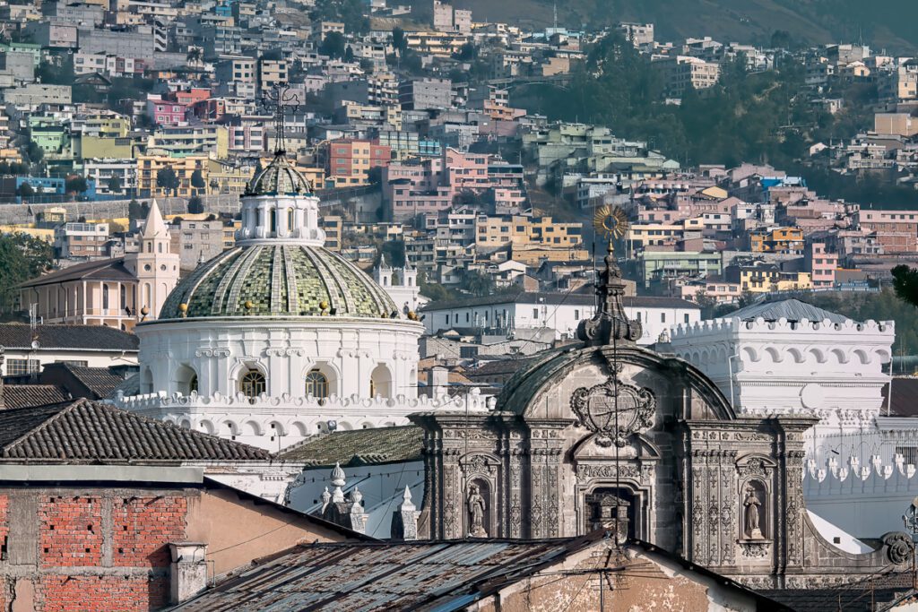 Colorful hillside view of Quito, Ecuador with historic domes and modern buildings.