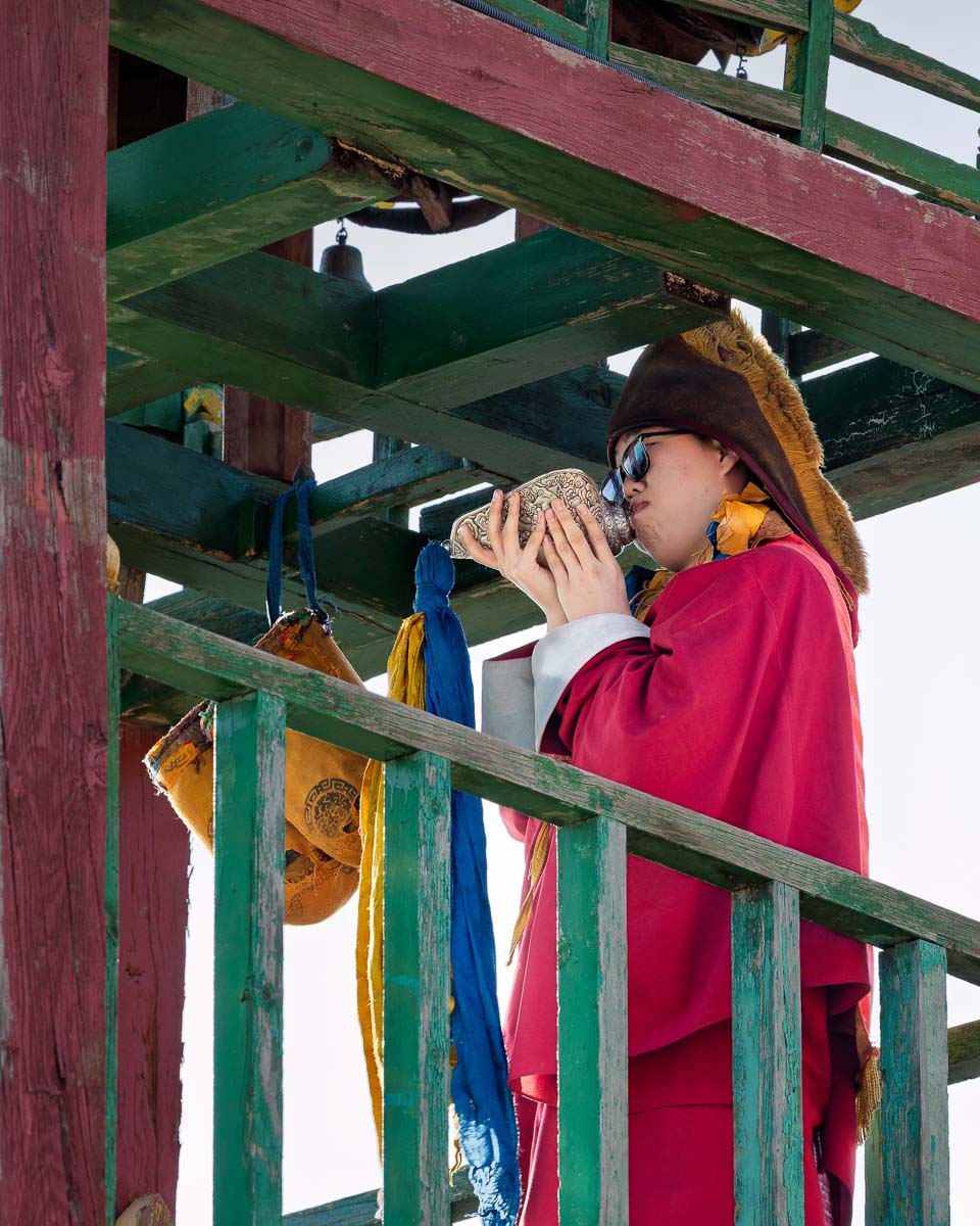 Buddhist monk blowing a ceremonial conch shell from a wooden tower at Gandantegchenling Monastery in Ulaanbaatar