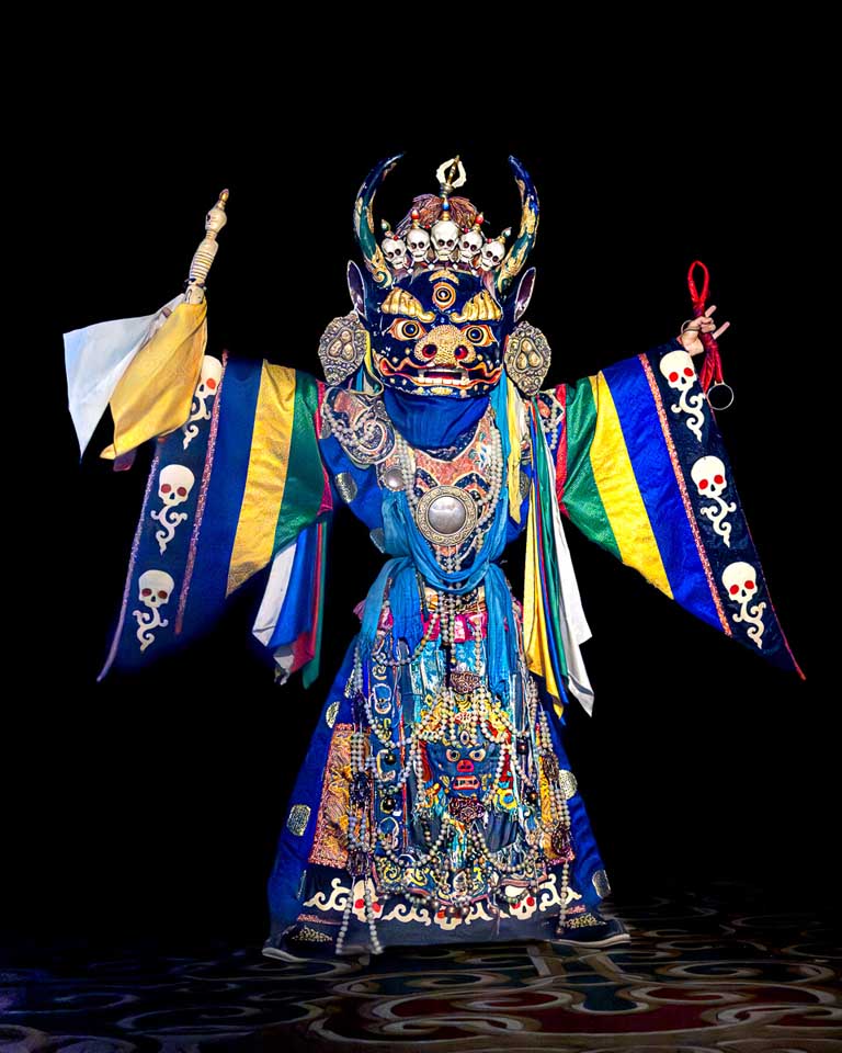 Performer from the Tumen-Ekh Folk Song and Dance Ensemble wearing an elaborate blue Tsam mask and embroidered ceremonial costume
